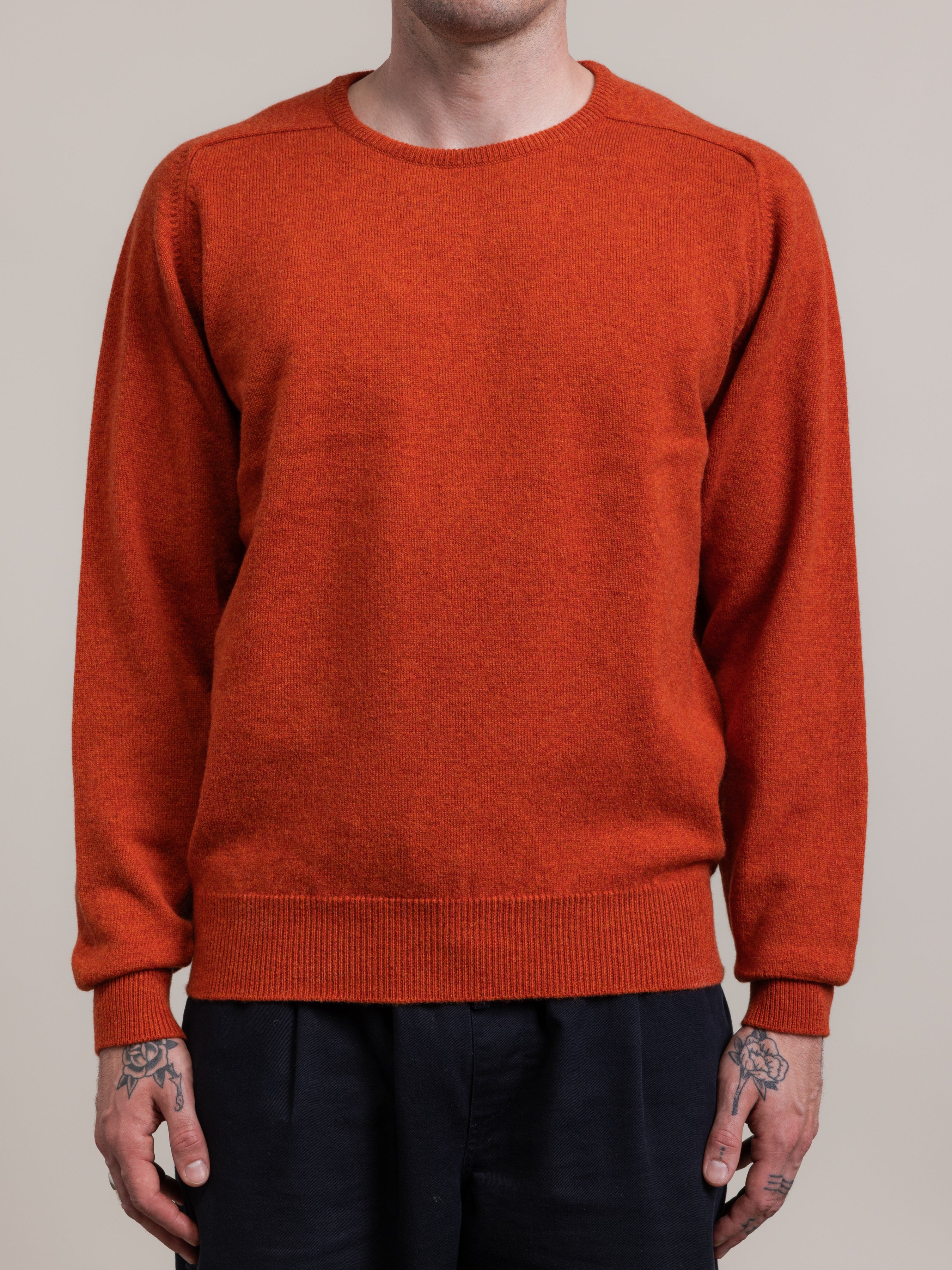 Person wearing a rust-colored sweater against a neutral background