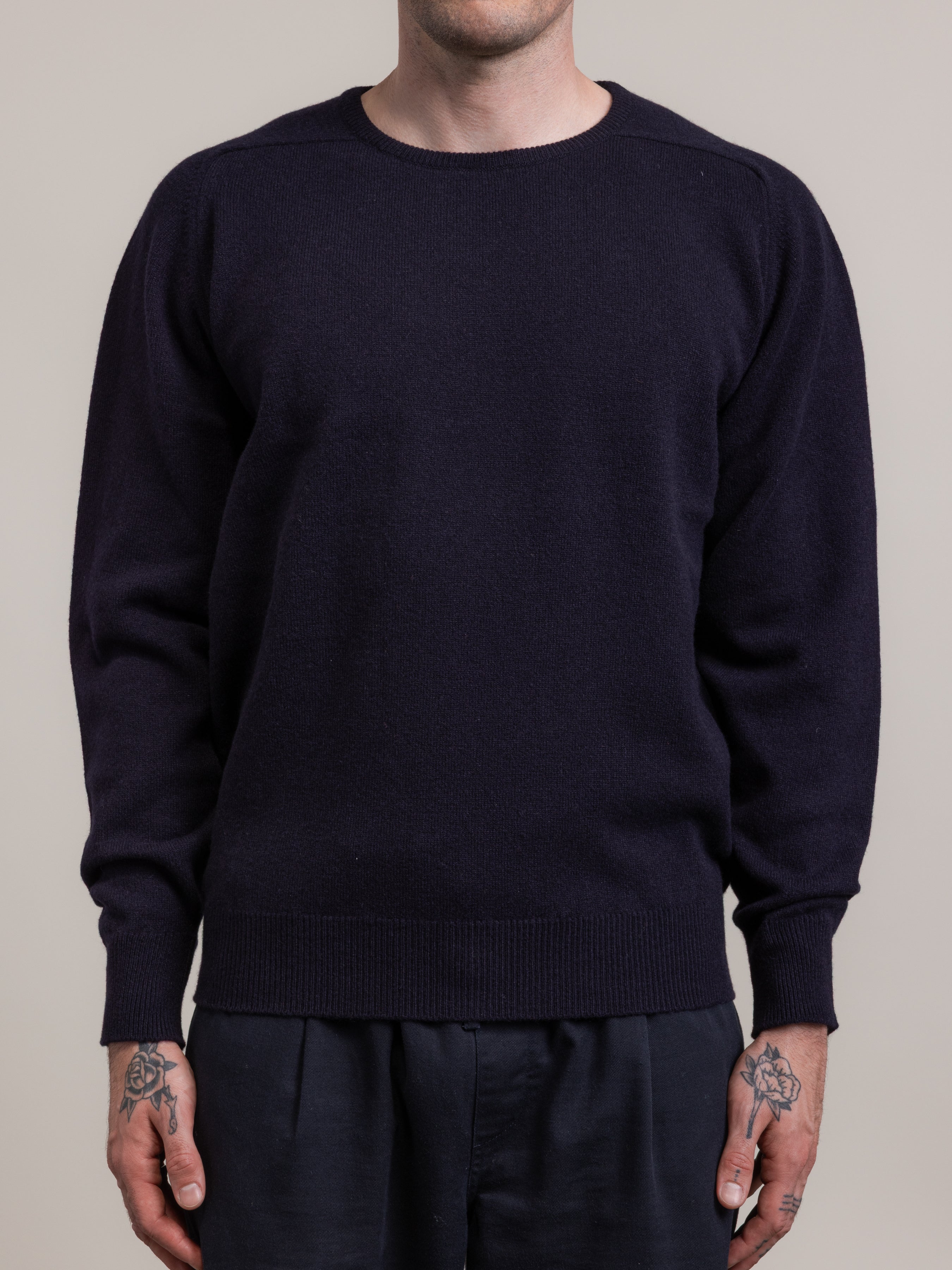 Man wearing a fine knitted navy blue sweater, made in Scotland.