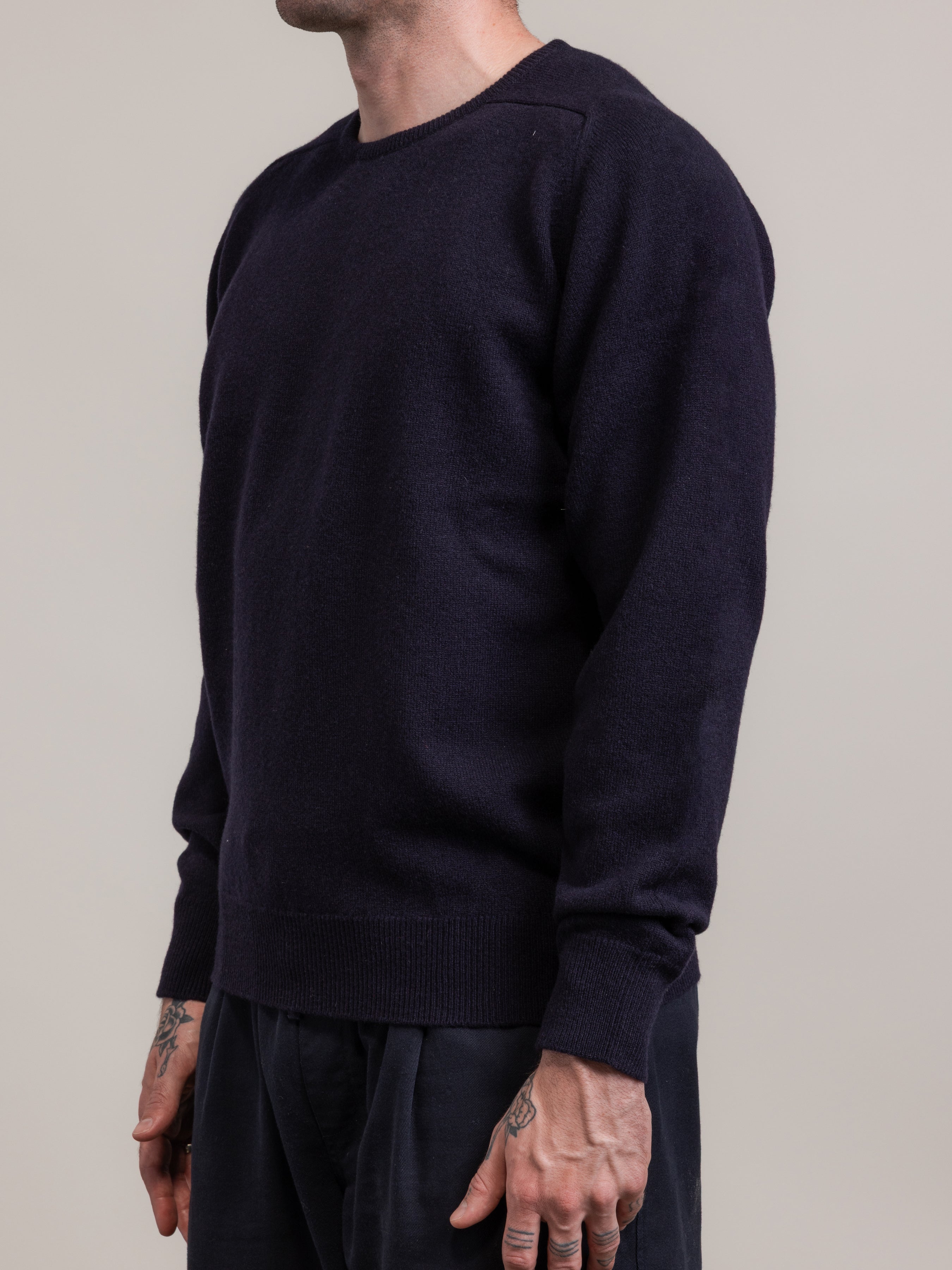 Person wearing a dark blue sweater against a plain background