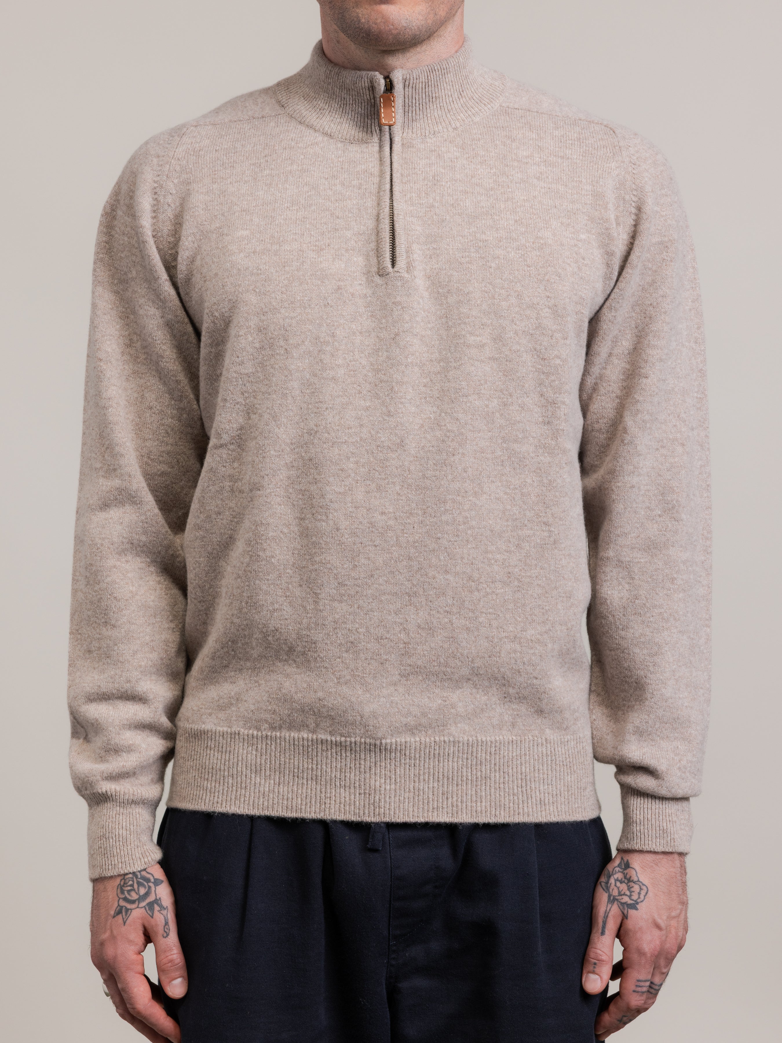 Beige sweater with a quarter zip worn by a person on a plain background