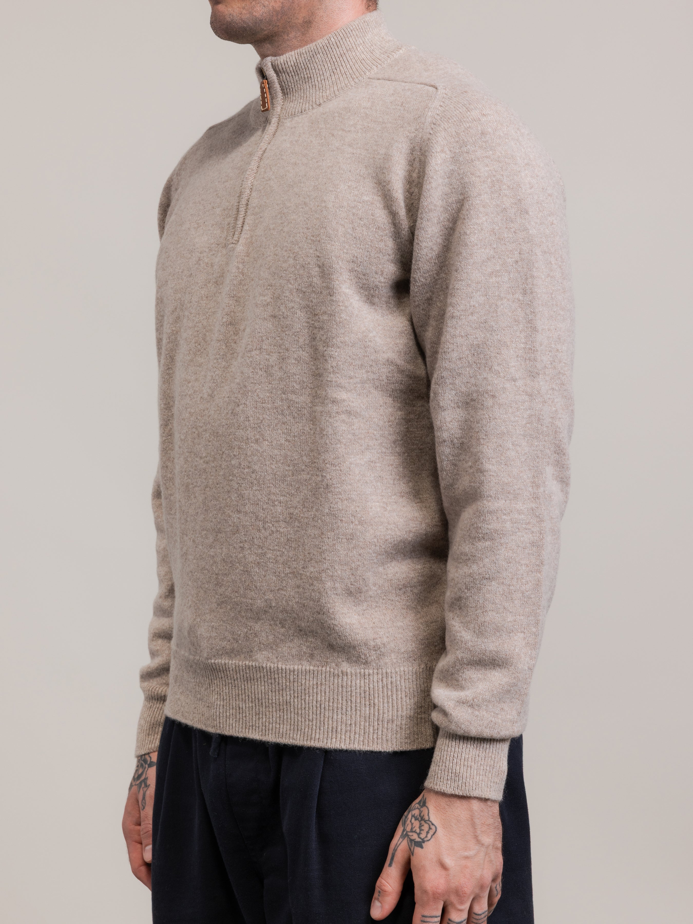 Person wearing a beige sweater against a plain background