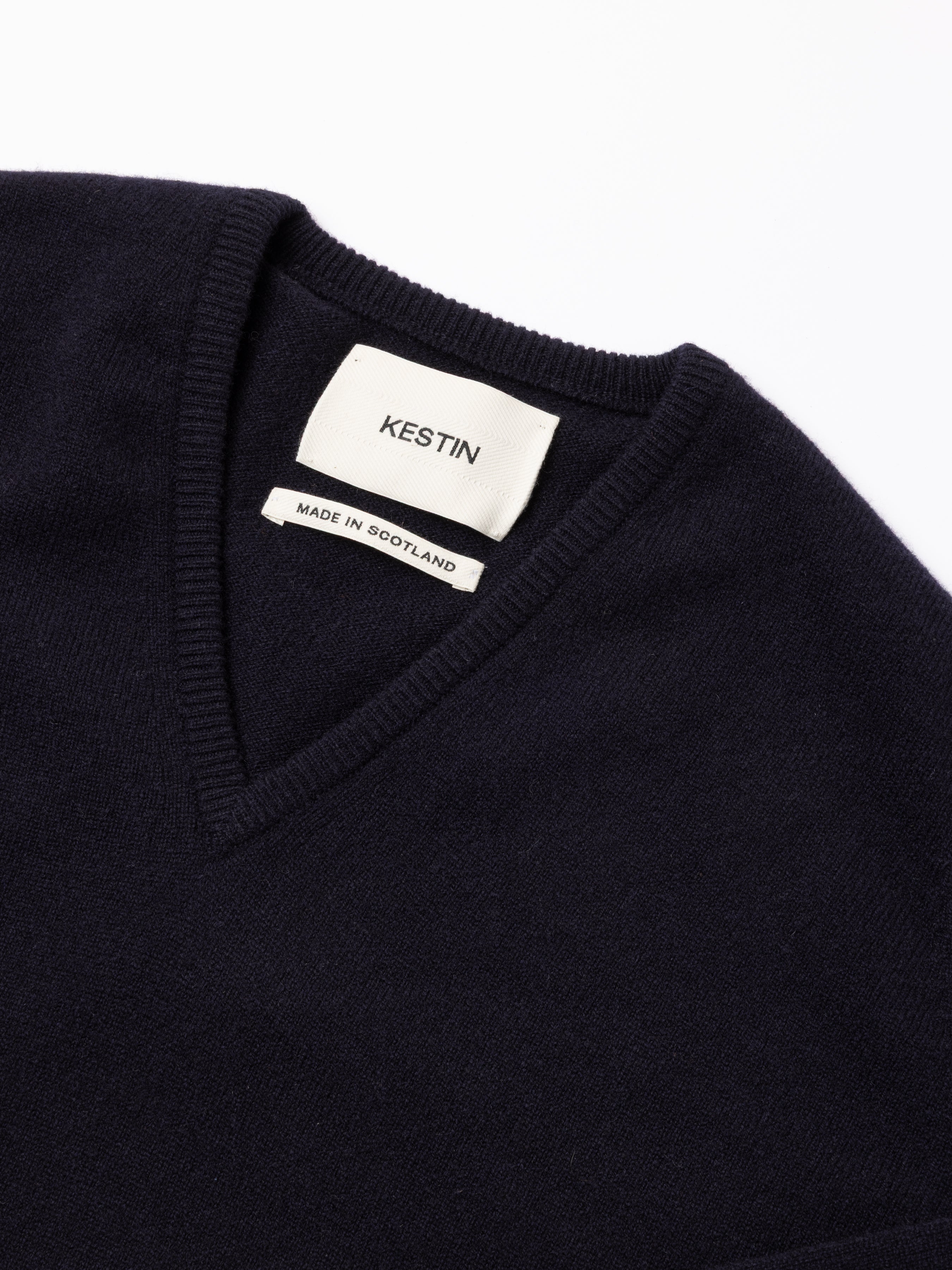 Navy blue v-neck sweater with a visible Kestin label on a white background