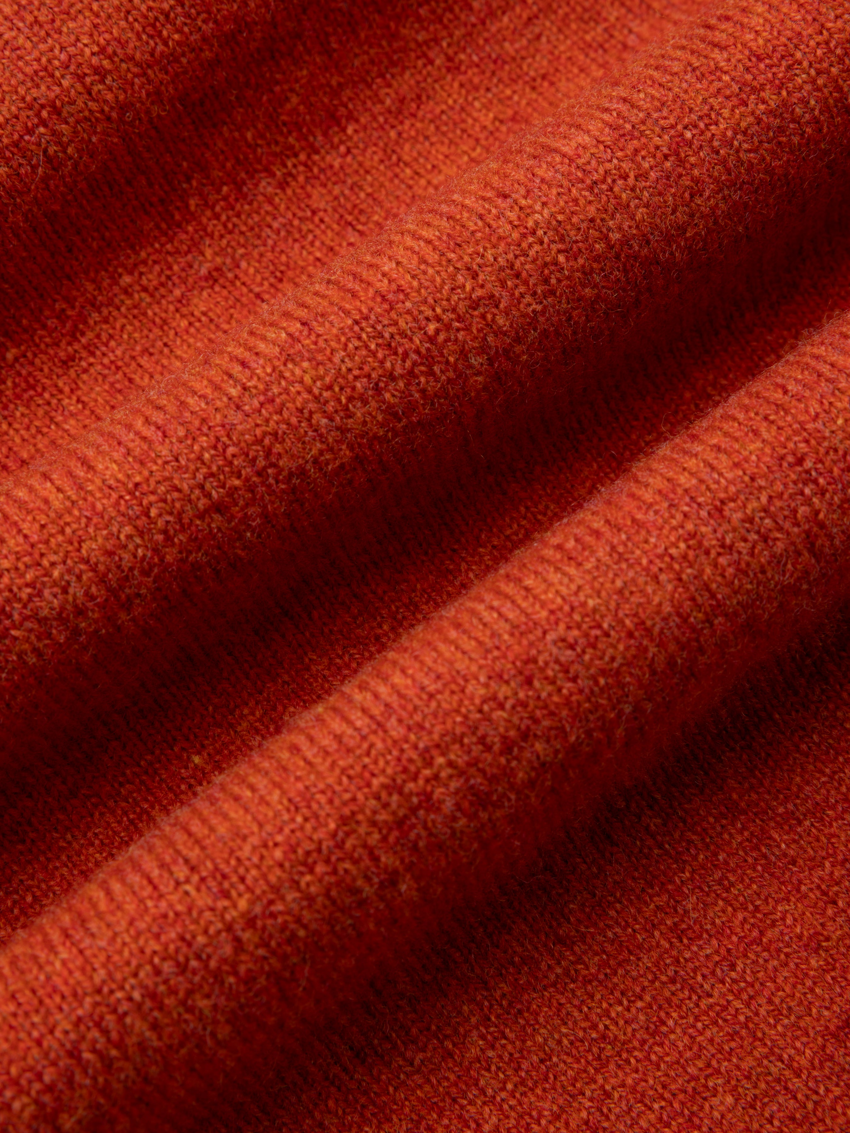 Close-up of dark orange fabric with a textured fine gauge design
