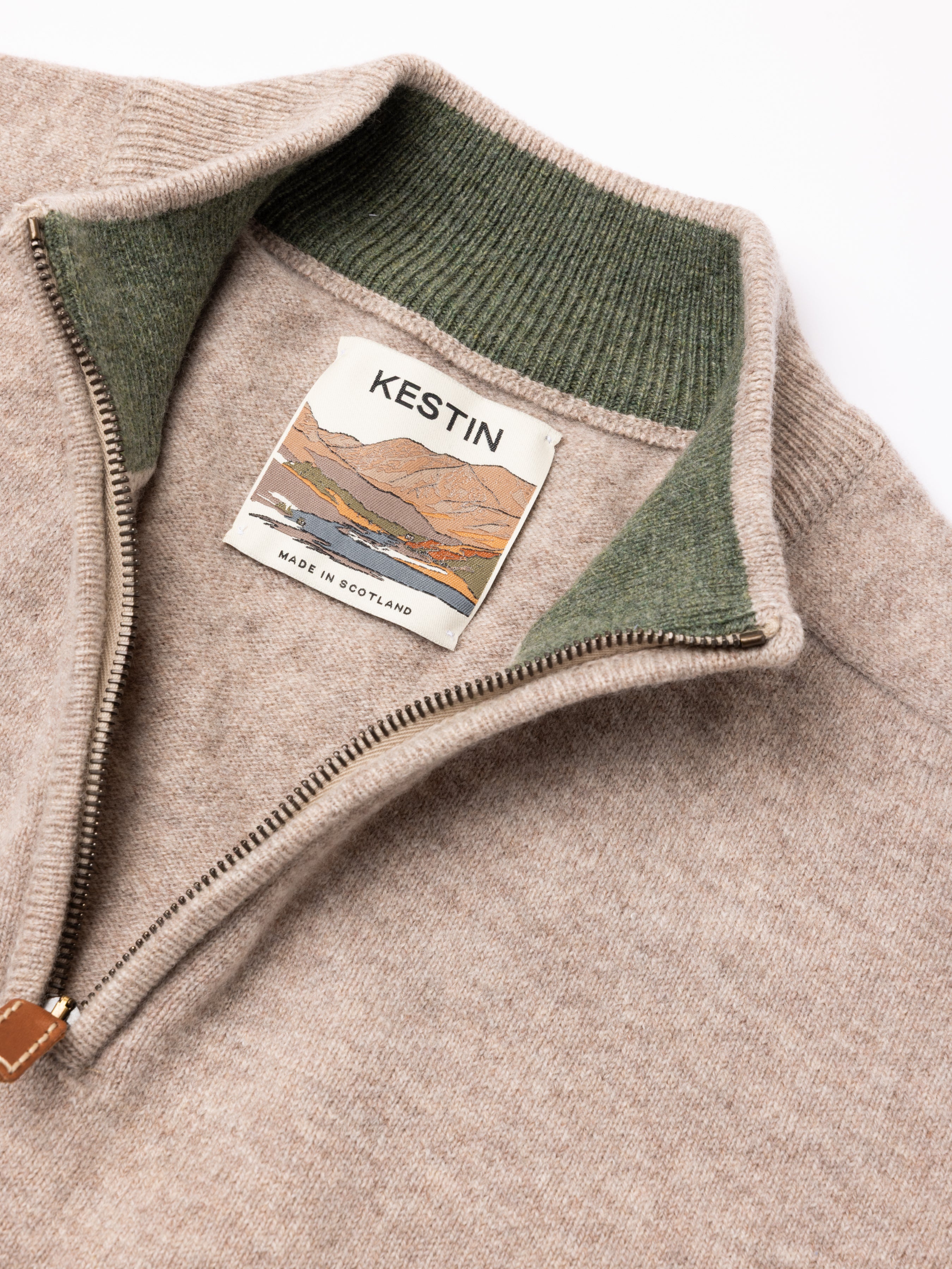 Close-up of a brown sweater with green collar and Kestin label on a white background