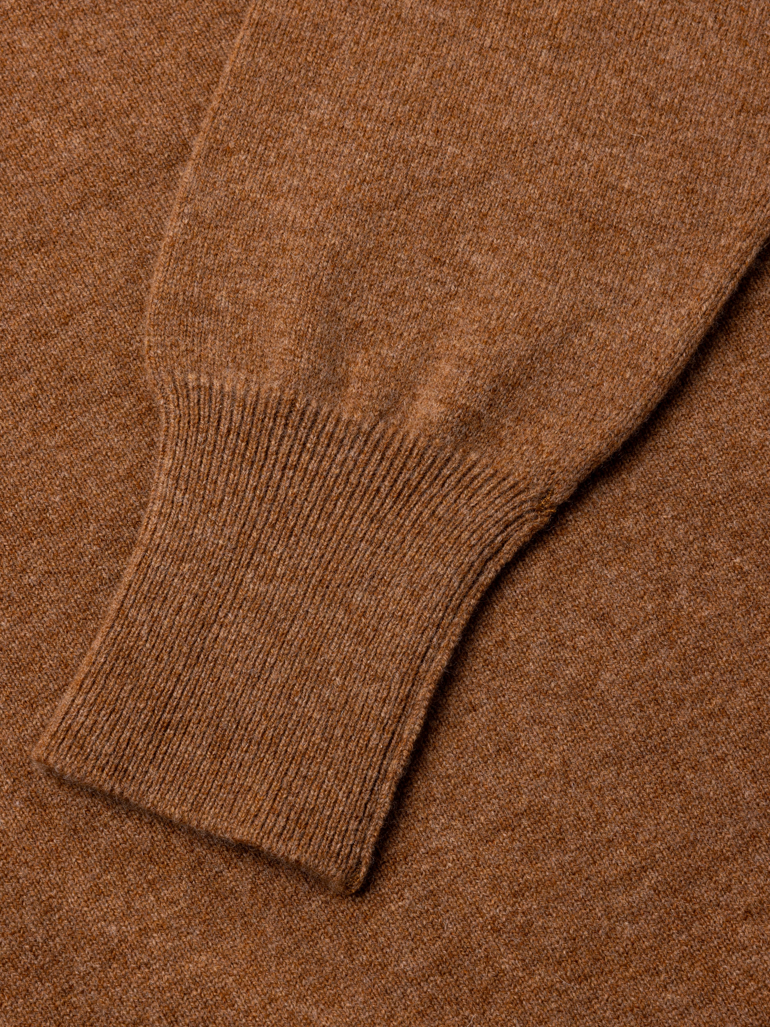 Close-up of a brown sweater sleeve with ribbed texture.