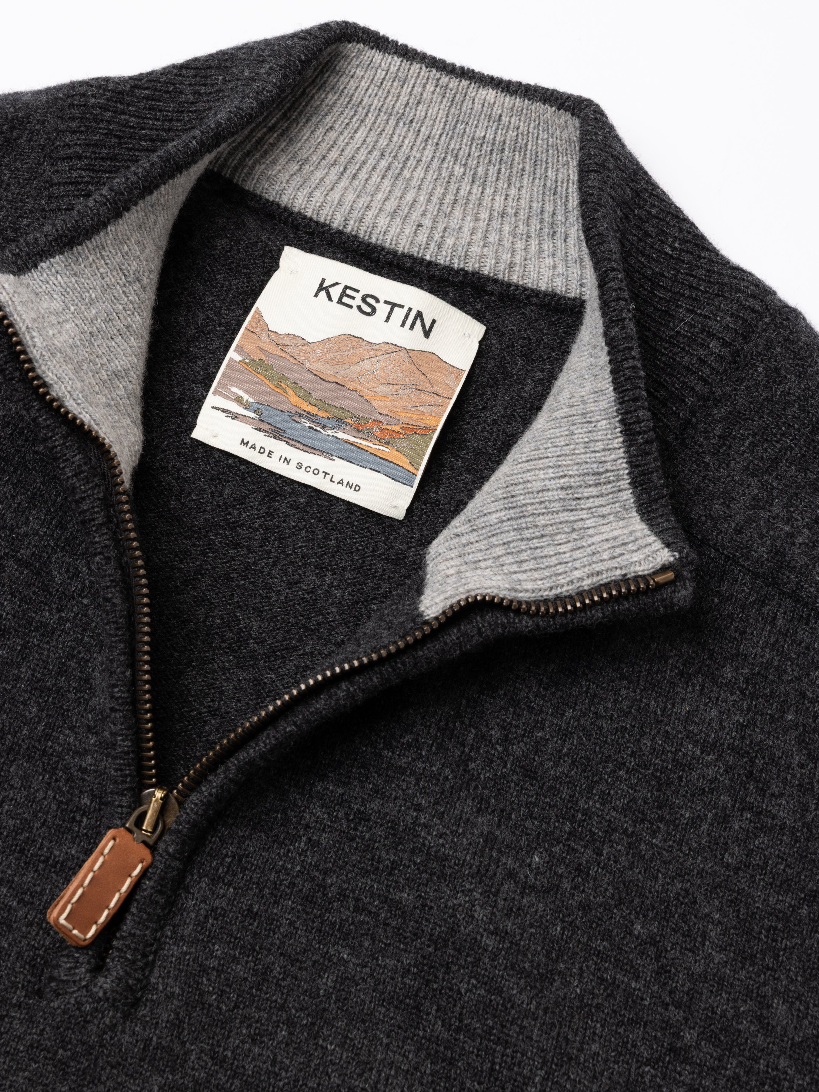 Close-up of a dark gray sweater with a Kestin label on a white background