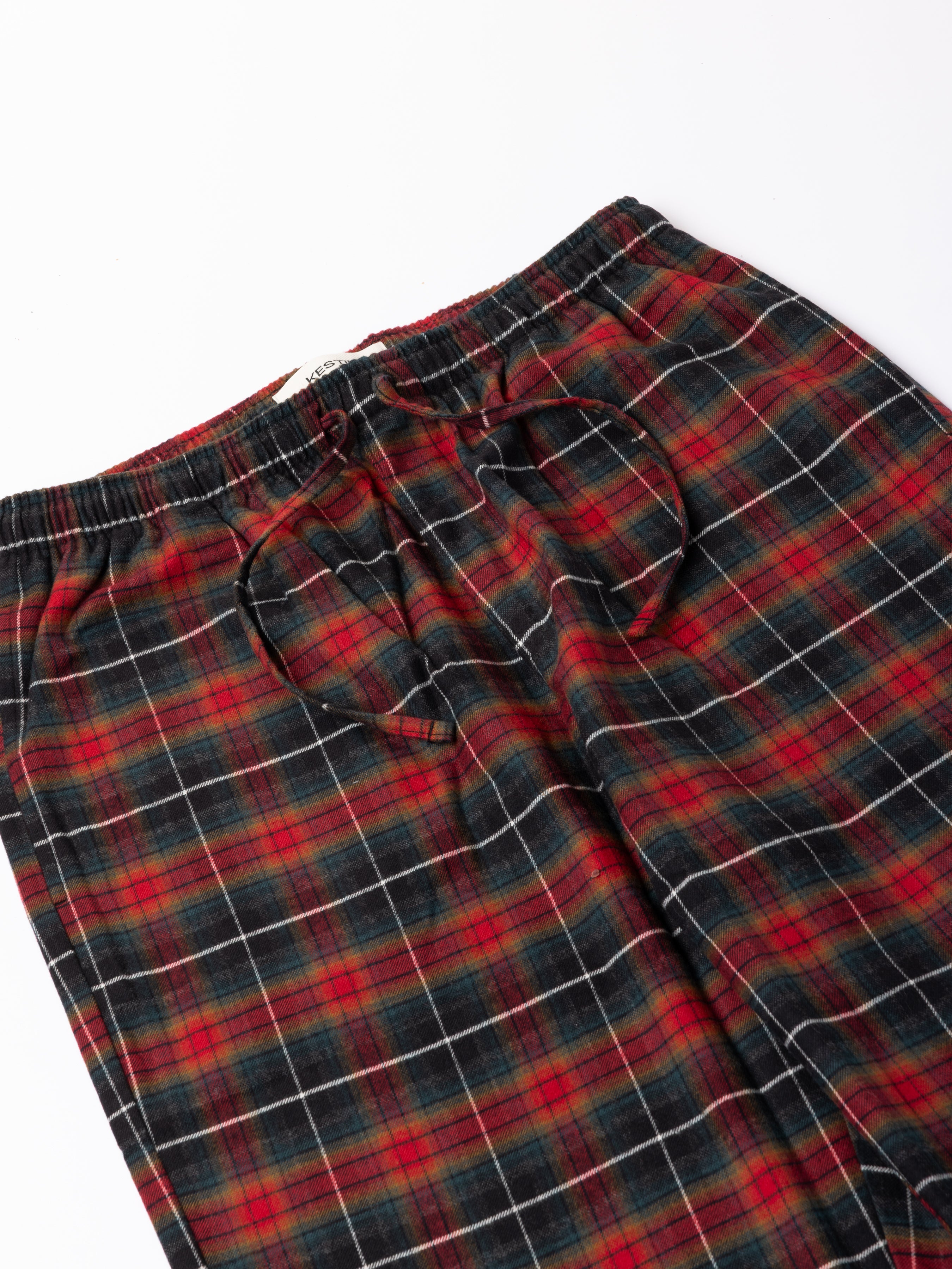 Plaid pants with red, green, and black pattern on a white background