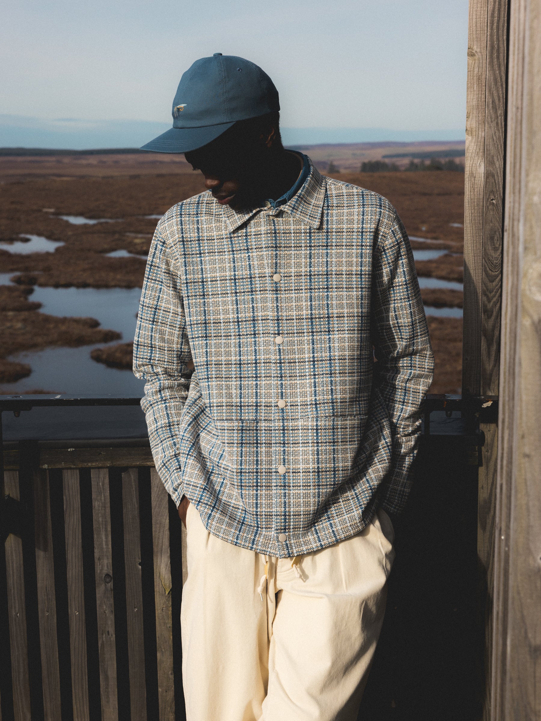 A man in the Scottish Highlands wearing a blue check jacket made from Italian cloth.