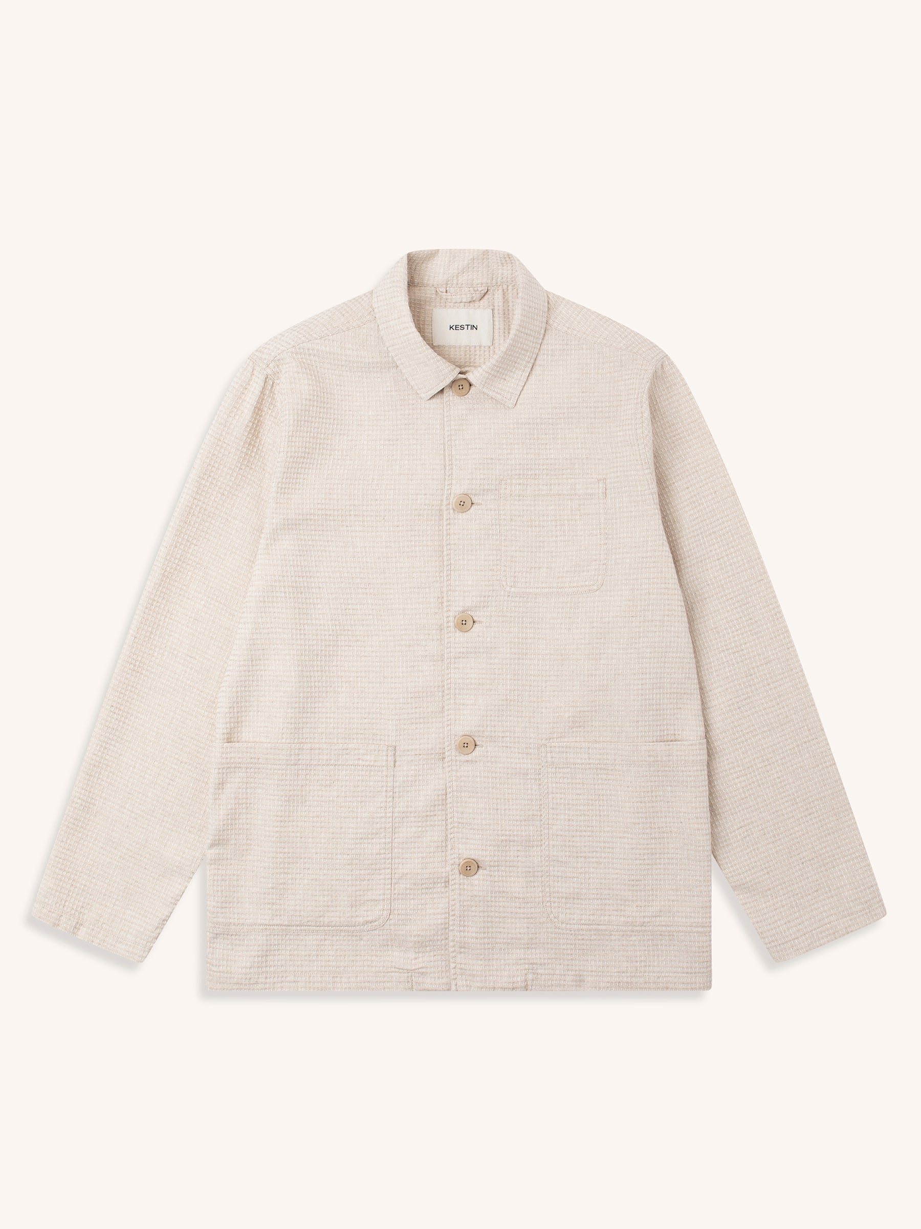 An ecru chore coat made from a waffle linen, on a white background.