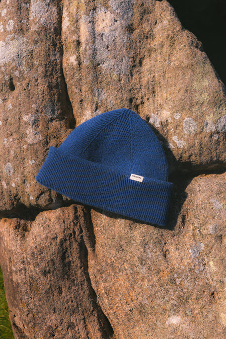 A cobalt blue beanie from KESTIN sitting on a rock.