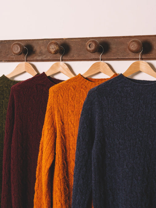 Four Cable Knit Sweaters hanging up, made from brushed Shetland wool.