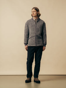 A model wearing a grey wool fleece with black corduroy trousers.