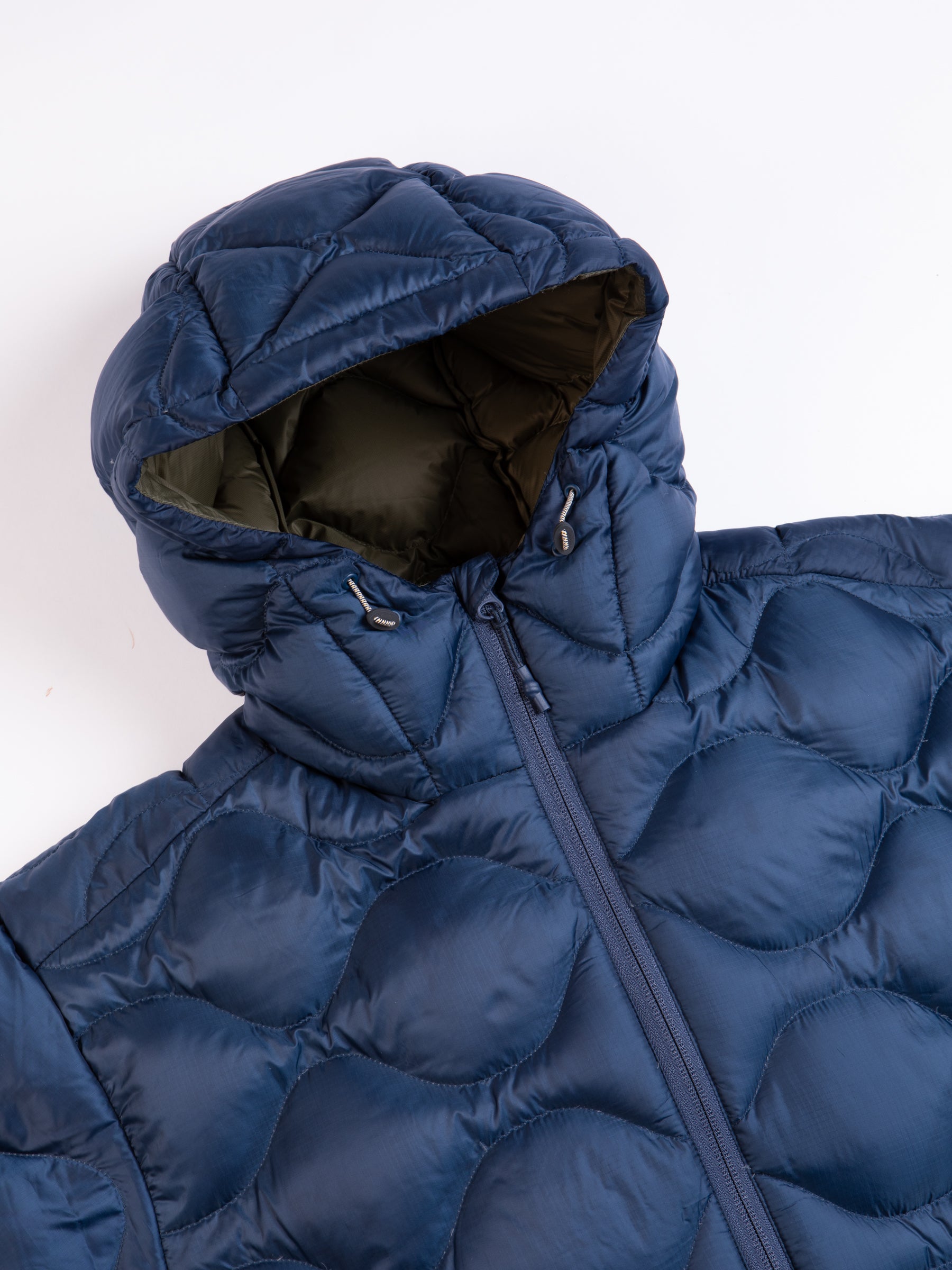 The hood of a quilted down jacket in blue on a white background.
