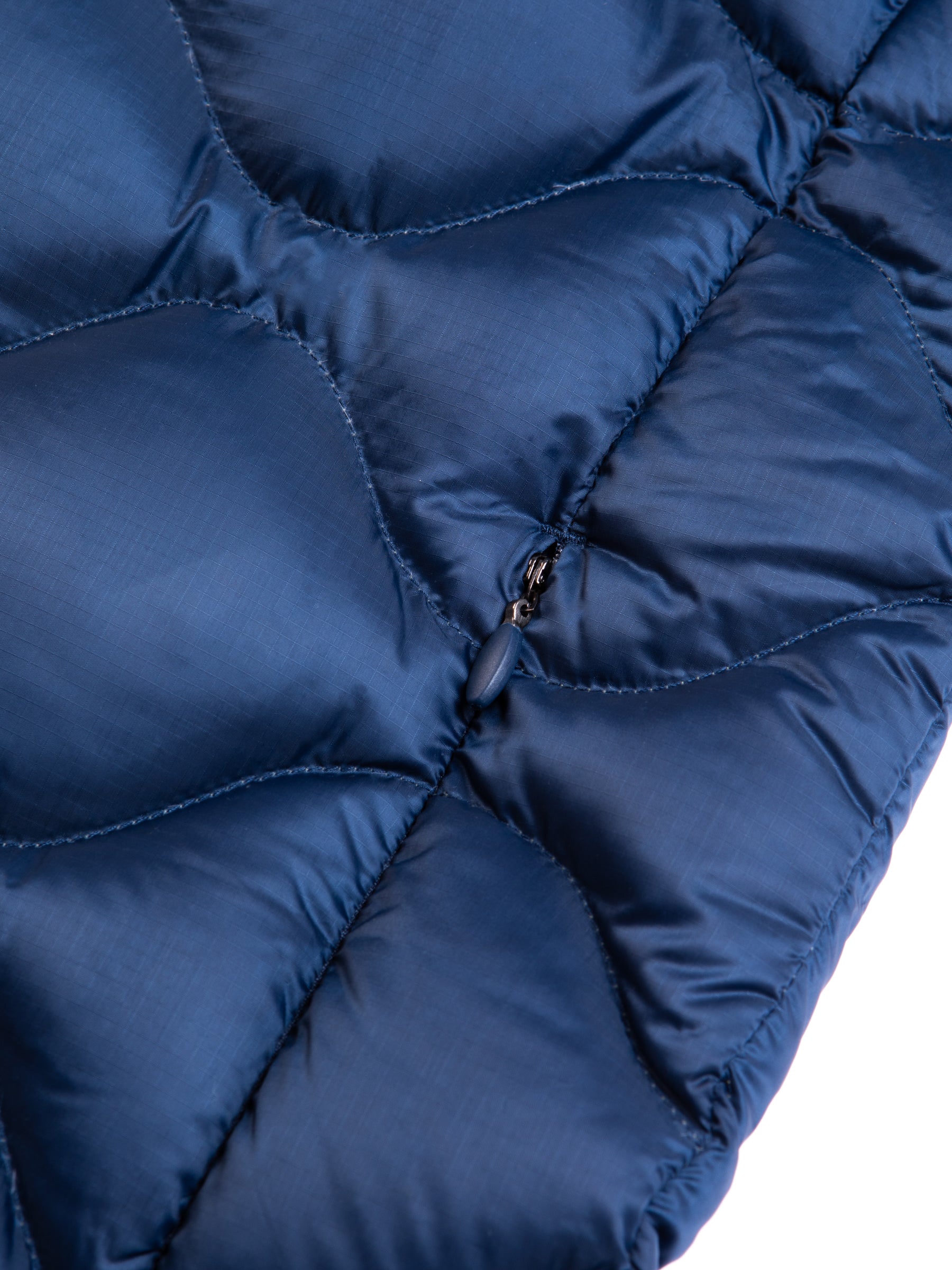 A zippered pocket on a blue quilted down jacket.