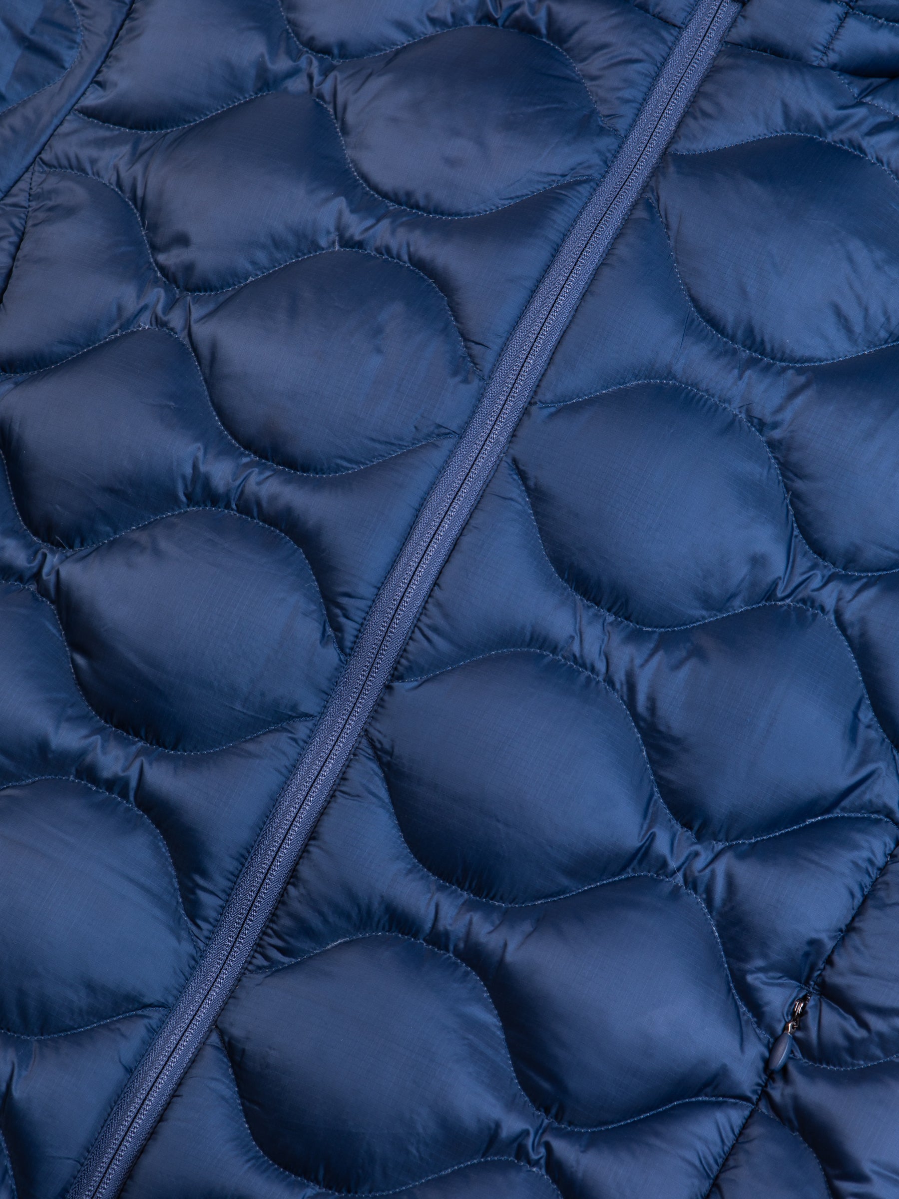 The material from a men's quilted down insulated jacket in a petrol blue colour.