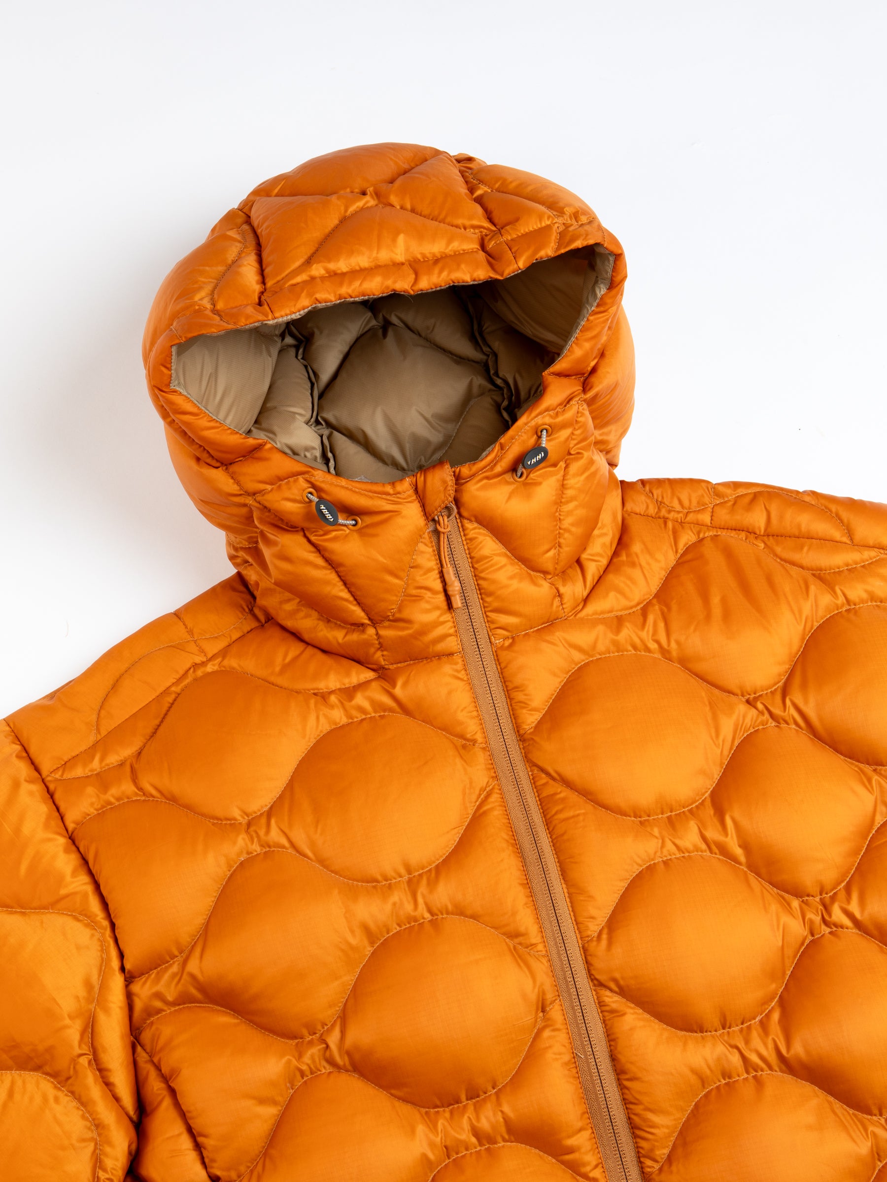 An insulated down jacket with a quilted design in orange, on a white background.
