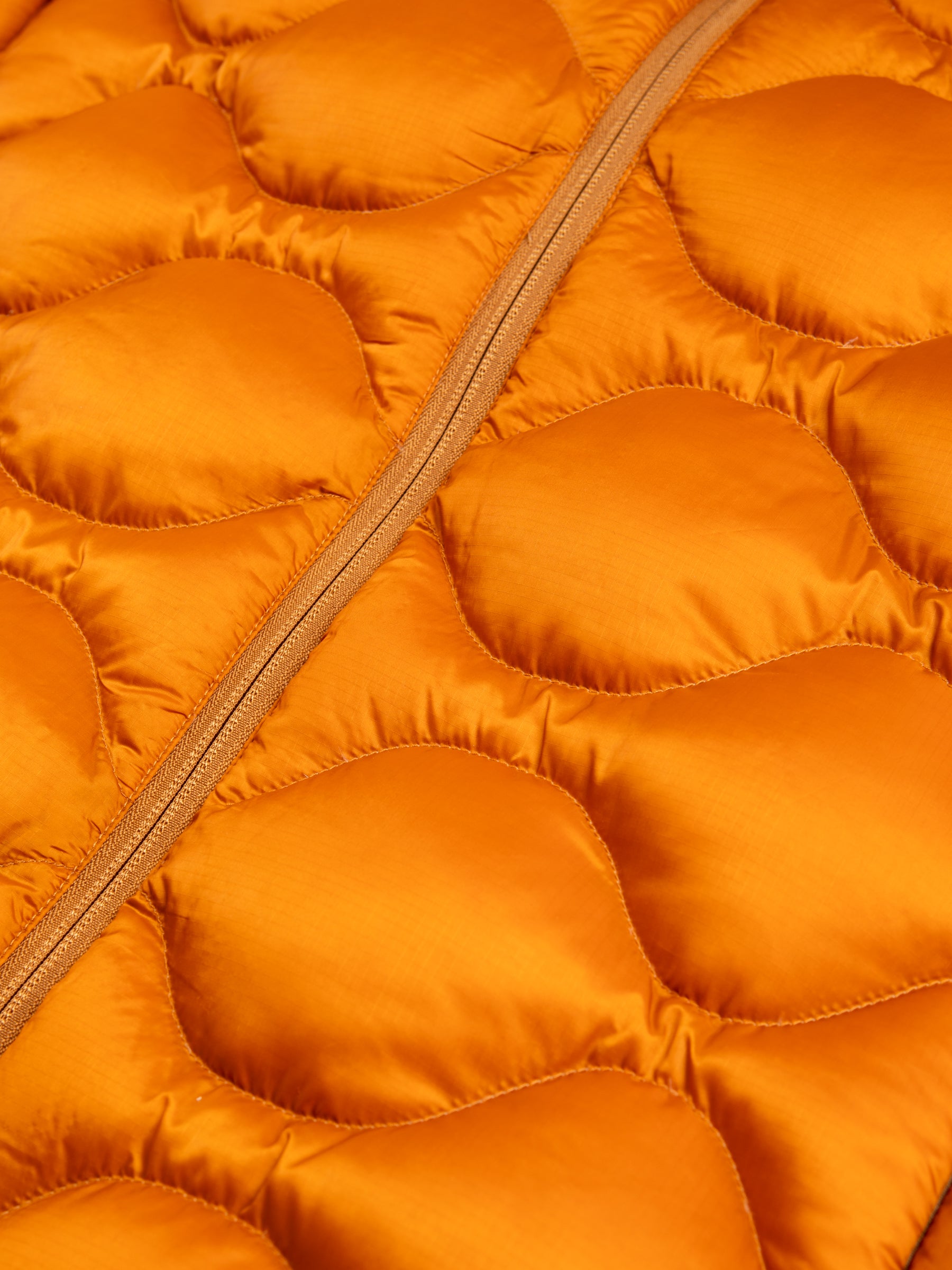 A quilted down jacket material in bright orange, using a ripstop material.
