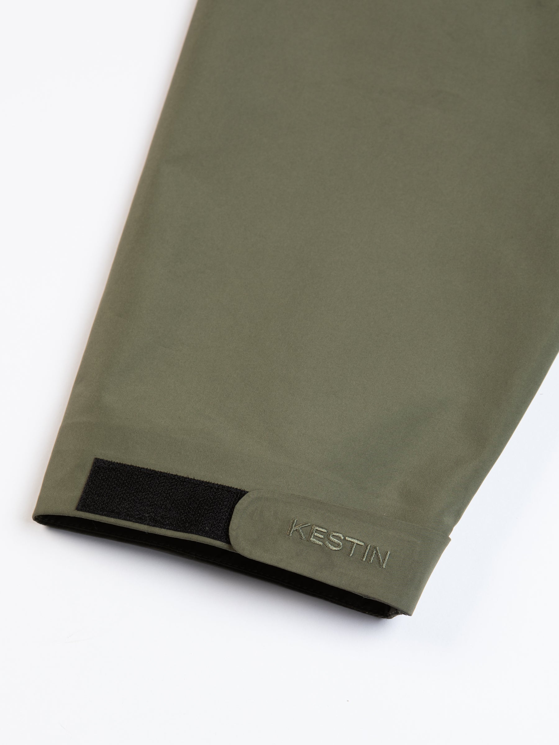 A Velcro strap to the cuff with an embroidered logo on a white background.