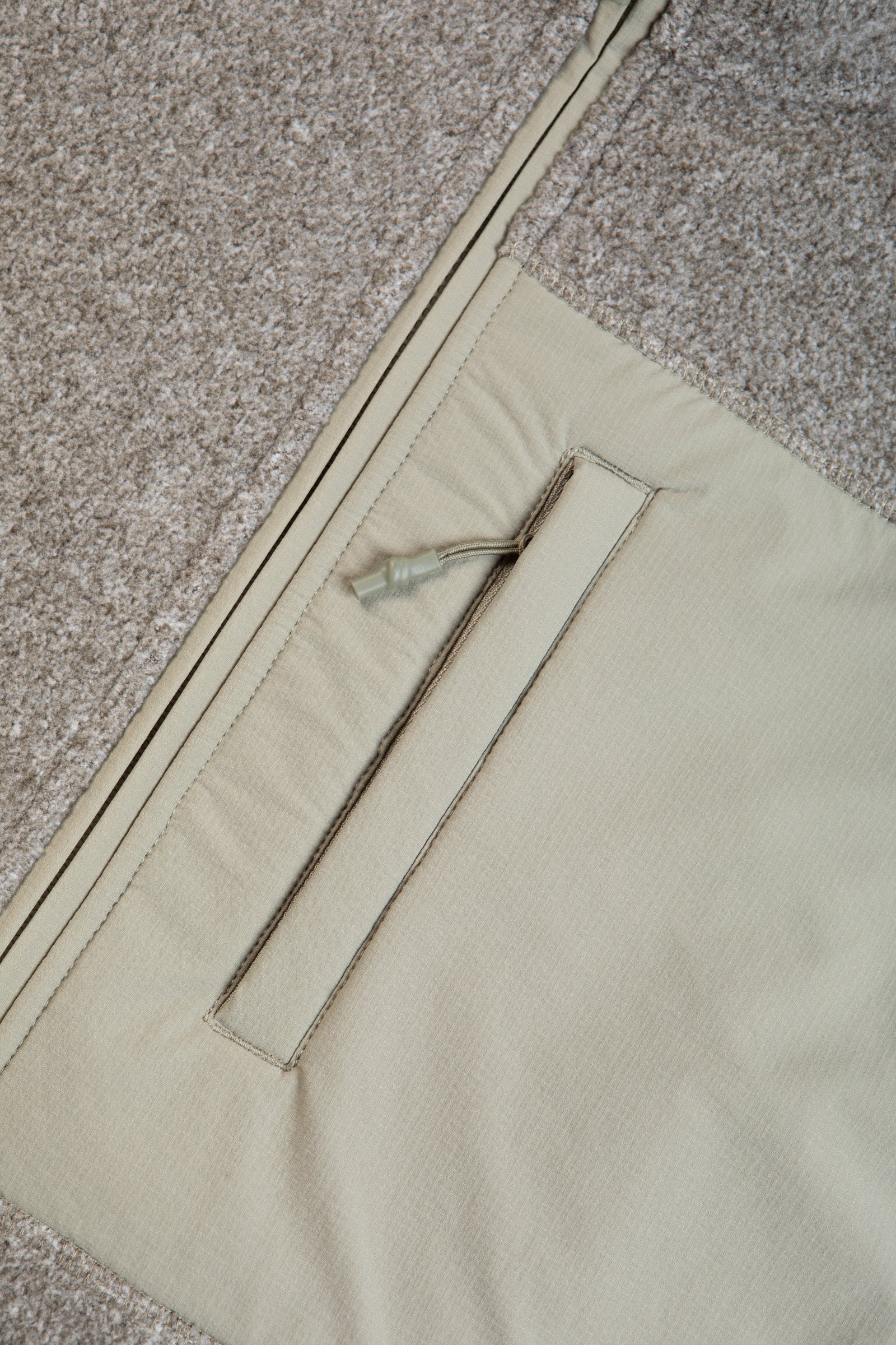 A zippered chest pocket on a men's recycled fleece in green.