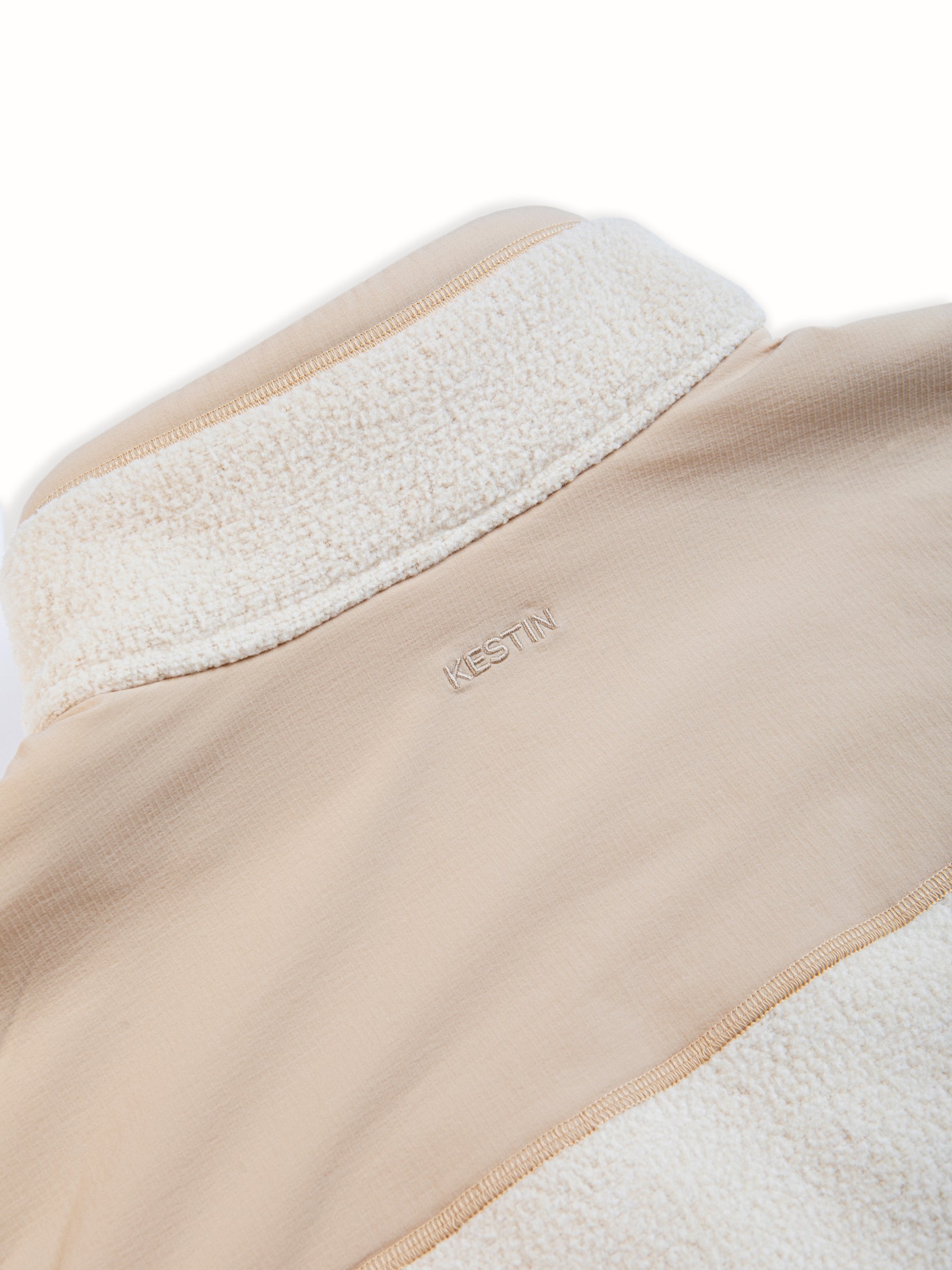 A warm fleece vest with a ripstop back panel in a cream colour.