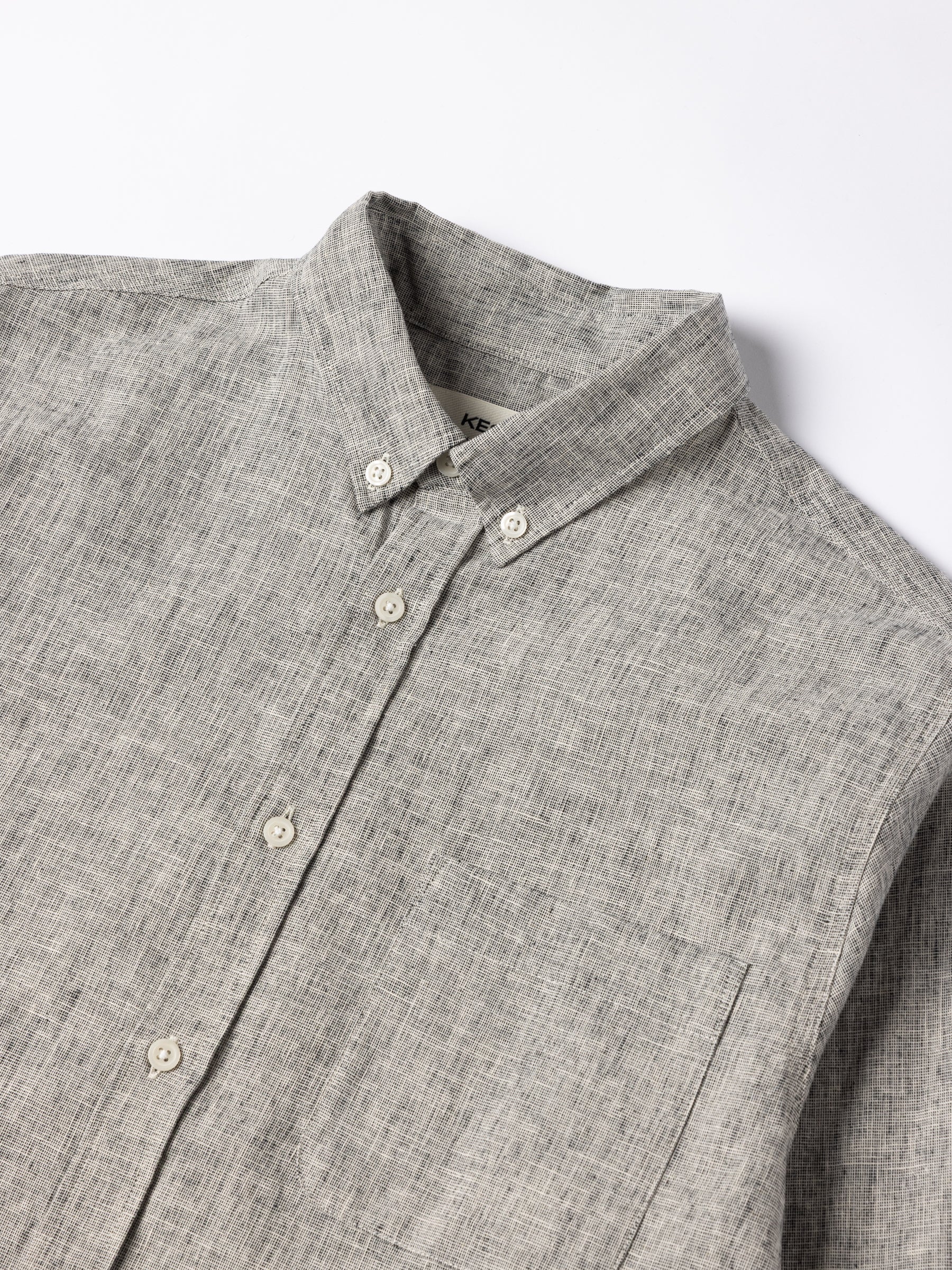 A close-up of the button down collar of the KESTIN Raeburn Shirt in ecru / black linen.