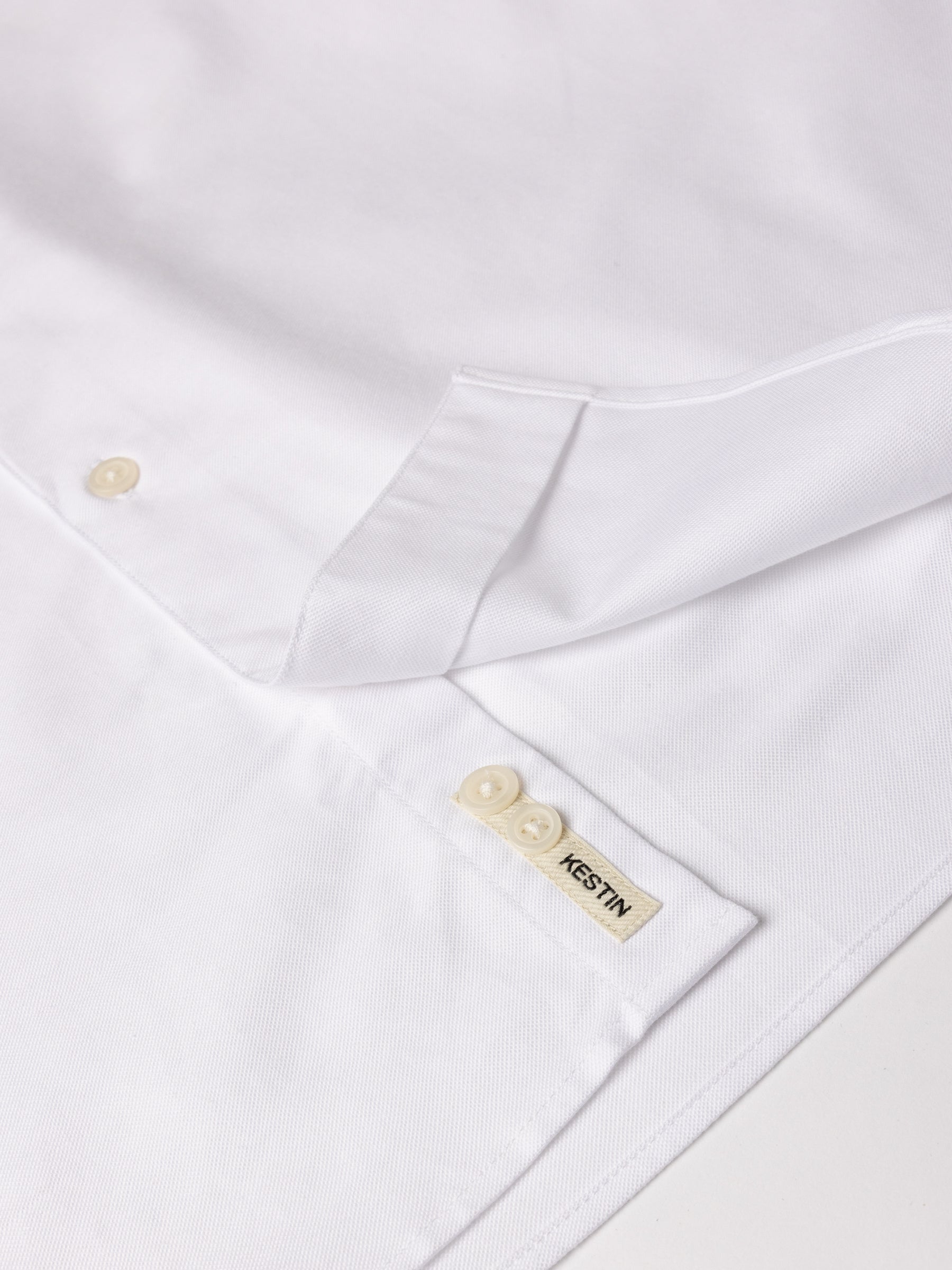 A close-up of the woven logo patch to the hem of the KESTIN Dirleton Shirt.
