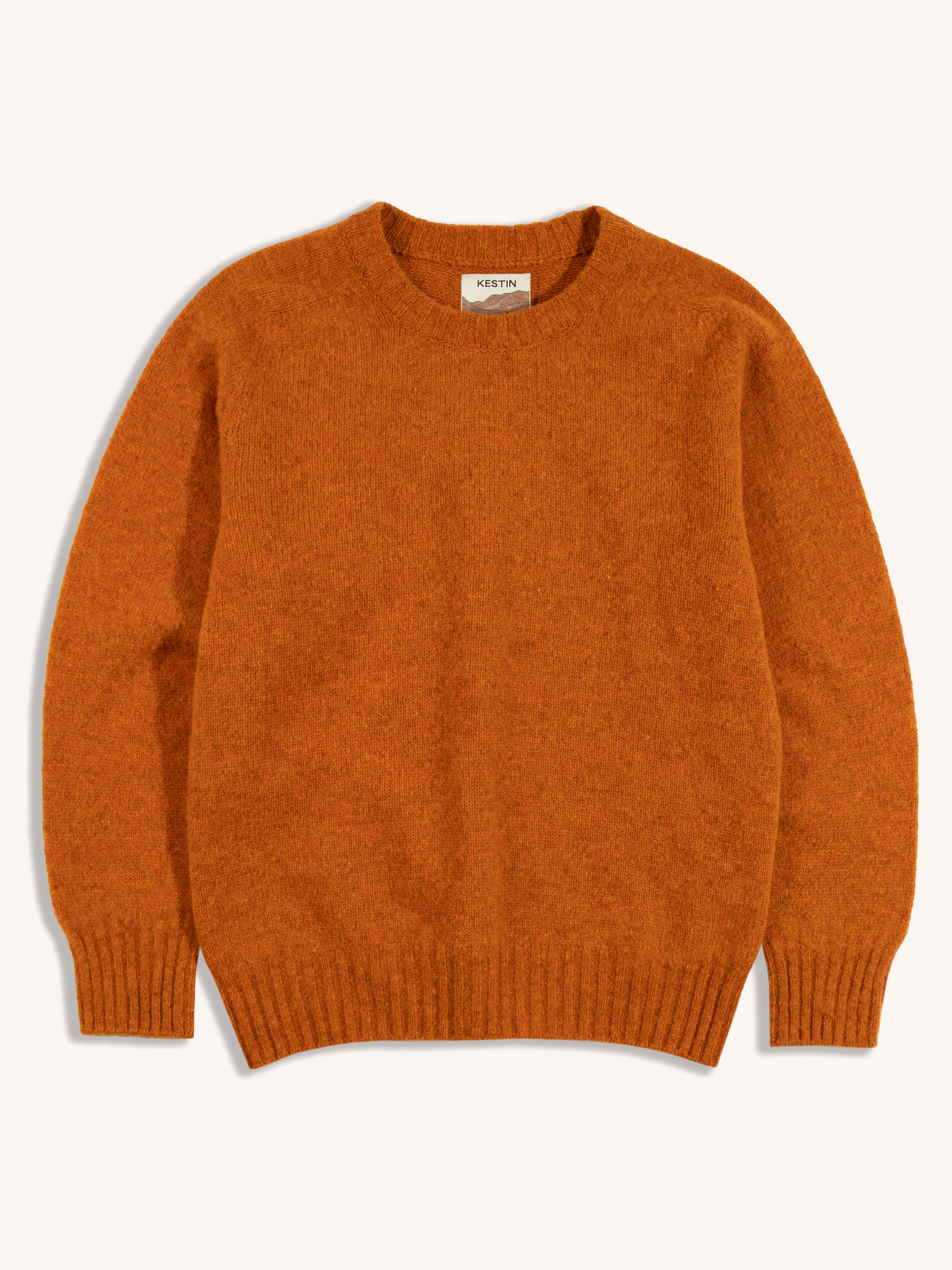 An orange sweater on a white background, made from a brushed Shetland wool.