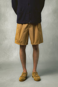 A model wearing tan brown shorts with brown shoes.