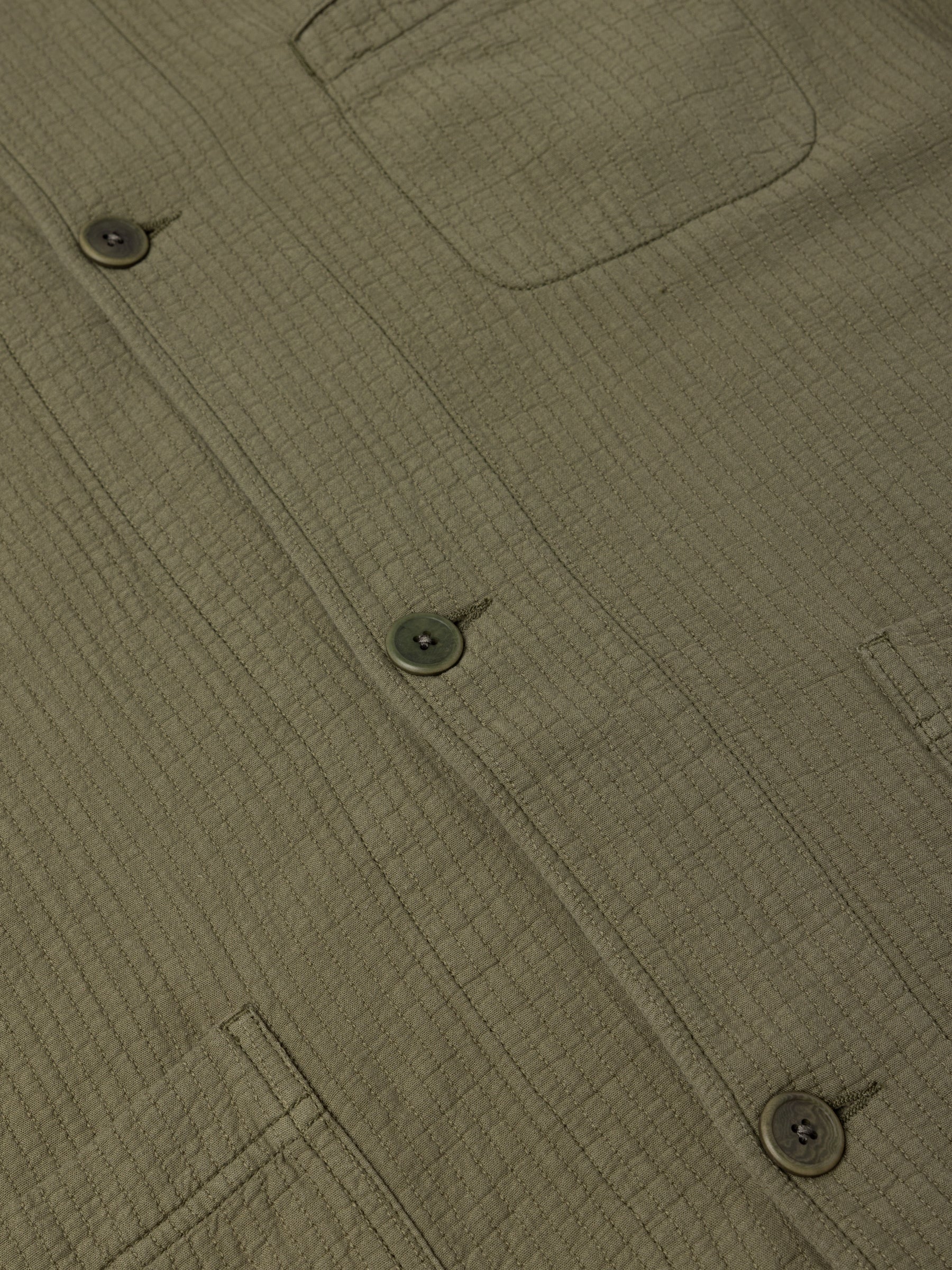 The buttons and patch pockets to the front of the KESTIN Huntly Jacket in olive green.