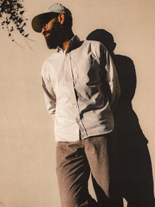 A man leaning against a wall, wearing clothing from Scottish menswear brand KESTIN.