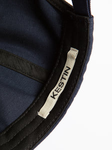 A woven logo tag sewn to the inside of a navy blue six panel cap.