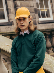 A model wearing a rugby shirt and a six panel cap by premium menswear brand KESTIN.