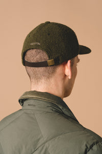 A man wearing a fleece cap and a heritage outdoor jacket, with down-filled quilting.