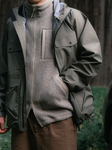 A man wearing a fleece gilet underneath a waterproof shell jacket.