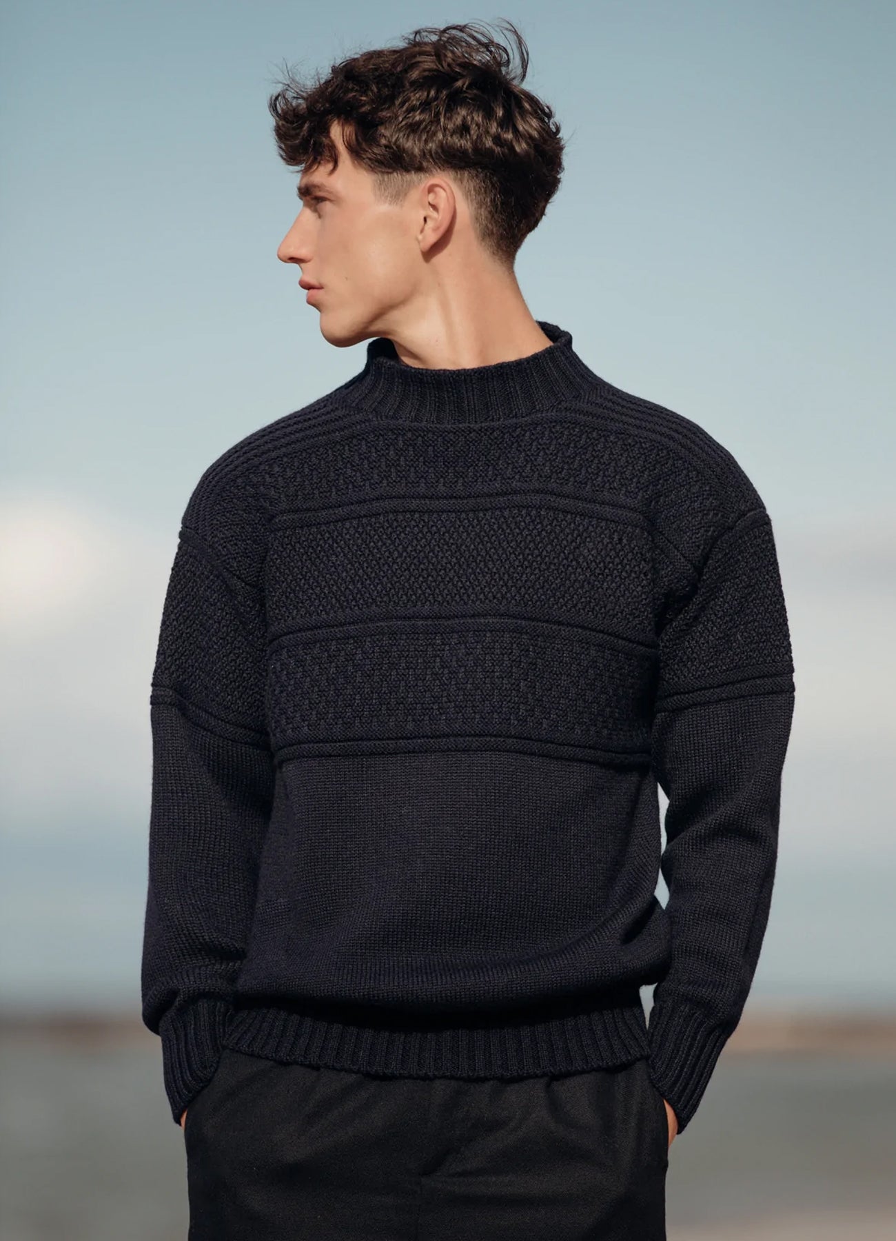 A man wearing a heritage knitted wool sweater, made in Scotland.