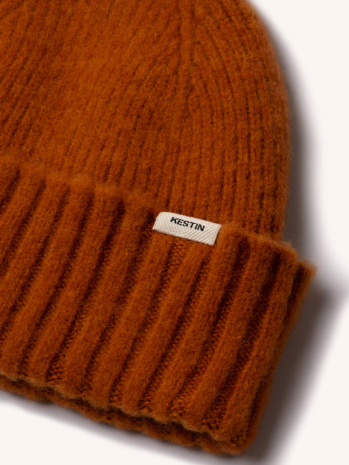 The woven logo tag to the KESTIN Balloch Beanie in orange.