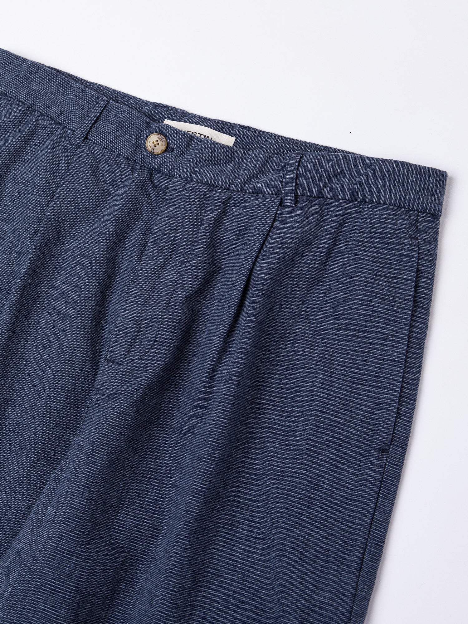 A close-up of the fixed waistband, button and fly of the KESTIN Wick Trouser in indigo blue.