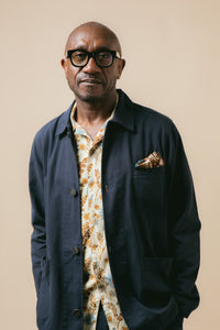 A man wearing a dark blue jacket and a floral shirt from the KESTIN SS24 Collection.