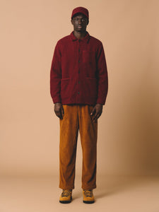 A model wearing a casual fall/autumn outfit, with corduroy trousers and a wool fleece chore coat.