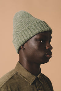 A model wearing a knitted wool beanie, made in Scotland by KESTIN.