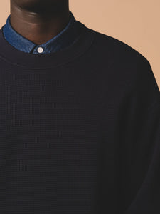 A model wearing a ribbed-crew-neck sweatshirt, in a dark navy waffle knit.