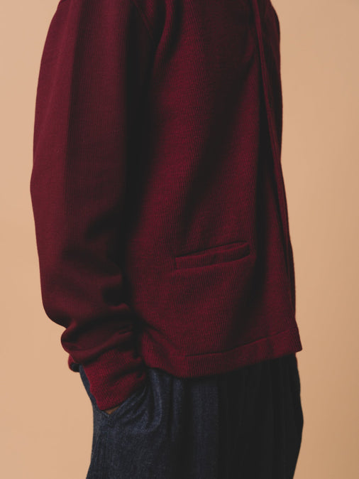 The side profile of a dark red cardigan, made from Japanese wool, designed by KESTIN.