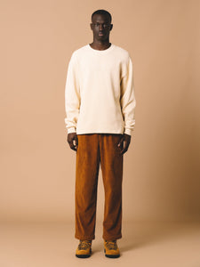 A model wearing a white waffle knit sweatshirt and brown corduroy trousers, by menswear brand KESTIN.