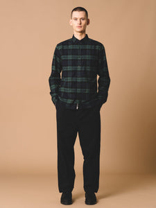 A model wearing the Wick Trousers and a Black Watch Tartan shirt by menswear designer KESTIN.