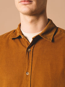 An unbuttoned collar, worn by a model styling the Dirleton Shirt, which is a long sleeve shirt made from a comfortable cotton corduroy.