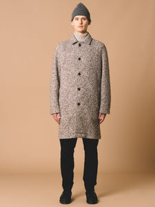 This model is wearing a fully-buttoned Overcoat, which is made from a premium Italian Wool, which is left undyed to show the natural grey colour.