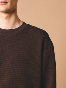 A model wearing a waffle-knit thermal crew neck sweatshirt in dark brown.