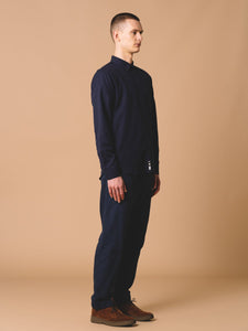 This model is showing the side profile of the KESTIN Raeburn Shirt, which is a long sleeve button-down in Navy.