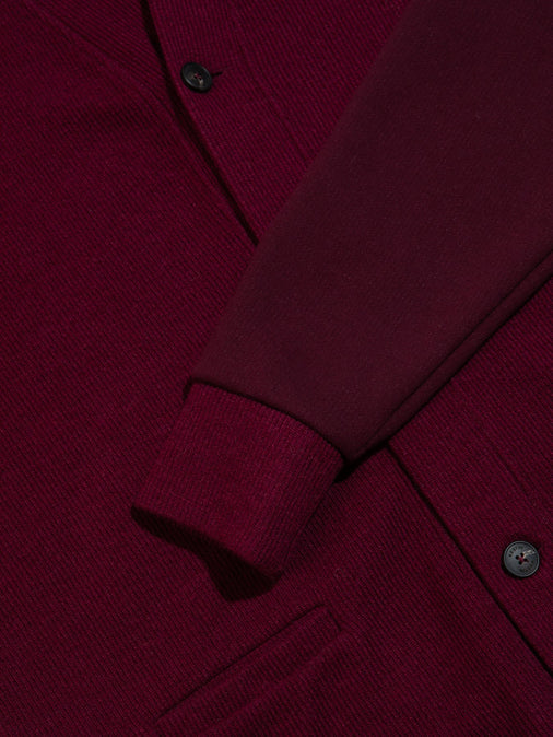 The ribbed cuff from a designer men's cardigan in a dark red colour.