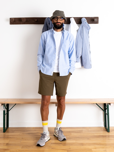 A man  wearing a casual summer outfit, featuring a classic men's Oxford Shirt, made from a comfortable 100% Organic Cotton in a Light Blue colour.
